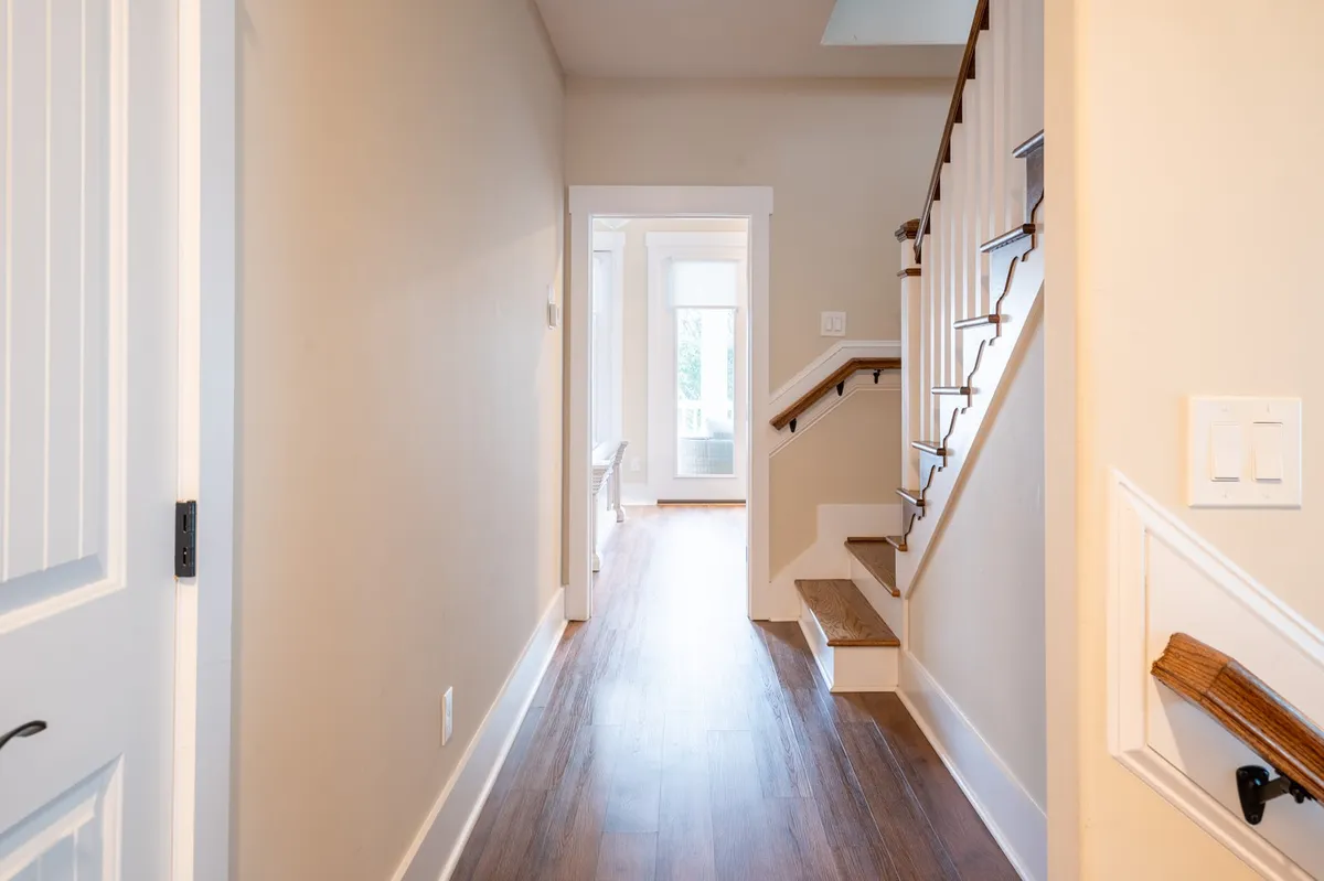 This image captures the first impression upon entering the home, featuring an inviting staircase, an open doorway, and wood flooring. The layout and warm ambiance hint at a welcoming environment perfect for guests gathering before heading out to nearby island events or returning home afterward.