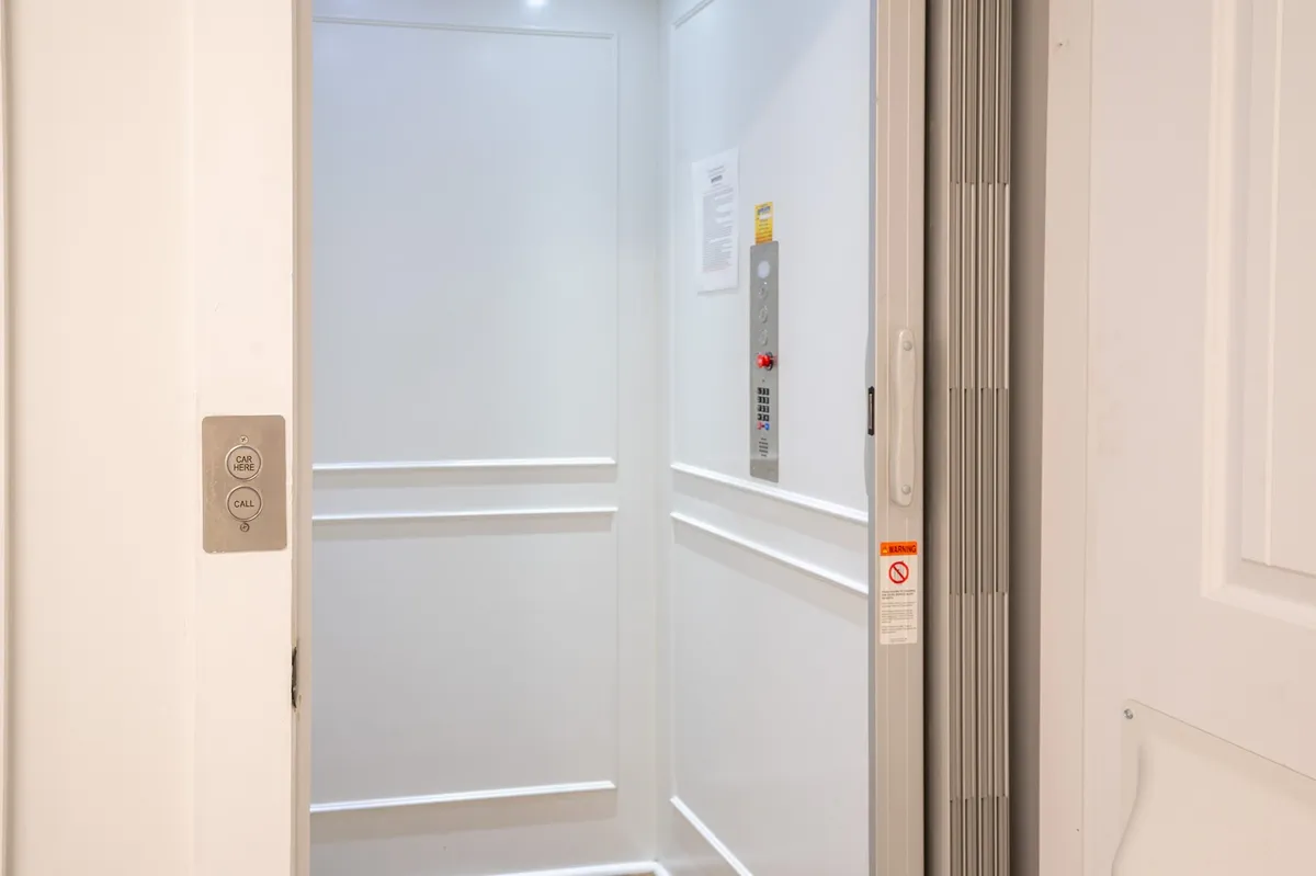 A neutral, well-lit interior elevator with a clear control panel and modern light fixtures. The smooth walls give a sense of ease and accessibility, suggesting a comfortable way to move between floors, especially when handling luggage.