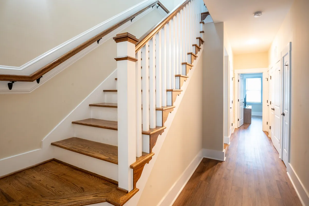 This interior shot showcases a bright hallway with a staircase and a doorway at the end, creating a sense of flow and anticipation. The space exudes an inviting mood, suggesting guests moving between rooms or preparing for excursions to local festivities.