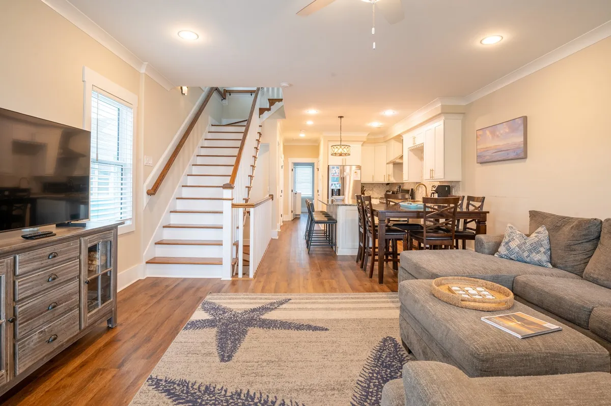 A cozy living space featuring a sofa, dining table, and staircase, with plenty of room for family gatherings and shared meals. The layout suggests comfortable communal spaces where guests can relax and recount their experiences.