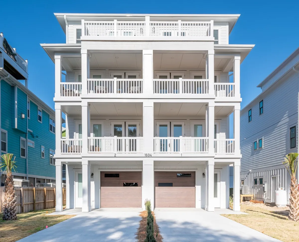 A three-story exterior view of the home, prominently displaying multiple balconies and garage doors. The structure suggests numerous vantage points for enjoying the outdoors, whether for sunrise coffee or sunset gatherings.