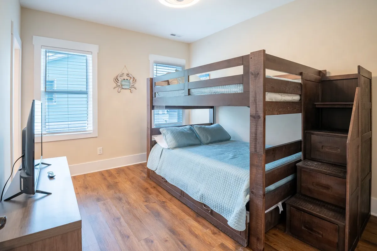 A cozy bedroom furnished with a bunk bed, a television, and wooden furniture. The setup provides a relaxed, family-friendly environment ideal for kids or additional guests.